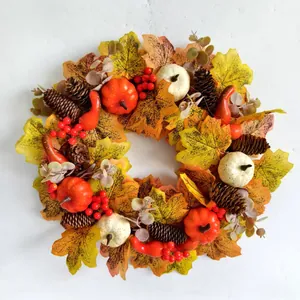 Detail shot of autumn wreath featuring pumpkins, pinecones, red berries, and maple leaves