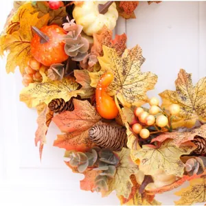Autumn wreath featuring pumpkins, pinecones, and maple leaves for Thanksgiving door decor.
