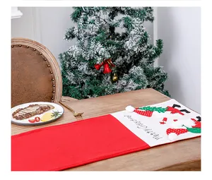 Embroidered Santa Claus detail on a red and white festive Christmas table runner