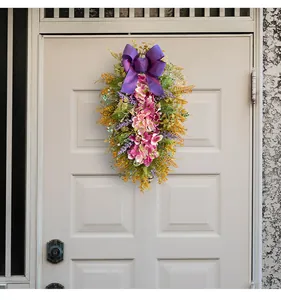 Detail of purple hydrangea teardrop wreath with a silk bow hanging on a white front door