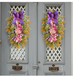 Detail view of two purple hydrangea teardrop swags with large bows on a grey door.