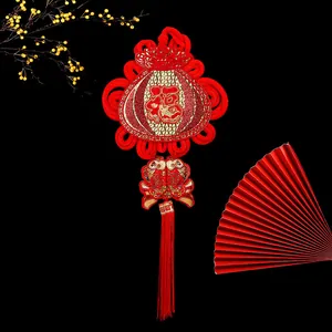Detailed view of red Chinese knot ornament with gold Fu character and koi fish embroidery.