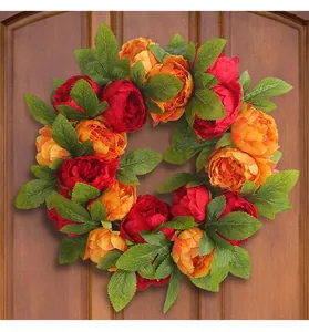 Detailed macro view of vibrant red and orange silk peony wreath displayed on a wooden door