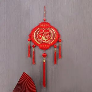 Traditional Chinese New Year red Fu ornament with tassels on a grey background.