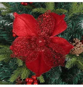 Close-up of a festive red glitter Christmas flower ornament on an evergreen tree branch