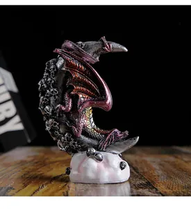 Gothic resin dragon statue perched on a crescent moon with skulls, intricate detail view.