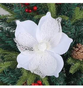 Detail of a white glittery Christmas flower ornament with lace petals on a tree branch.