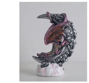 Detailed view of a gothic dragon statue perched on a skull-studded crescent moon