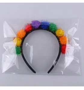 Detailopname van een kleurrijke glitter pompon haarband in een doorzichtige verpakking.