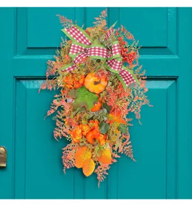 Detail of an autumn door wreath with pumpkins and maple leaves on a turquoise door.