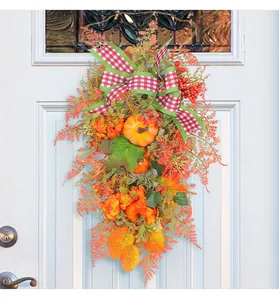 Detailed view of an autumn wreath with pumpkins and a checkered bow on a white door.