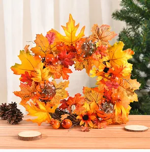 Detail view of autumn wreath with maple leaves and pumpkins on a rustic wooden table