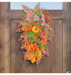 Close-up detail of autumn pumpkin wreath with red checkered bow on wooden door
