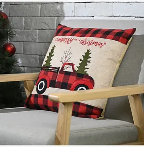 Detalle de funda de cojín navideño con camión rojo y estampado de cuadros rojos.