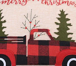 Detalle del bordado de camión navideño de cuadros rojos y negros en funda de cojín