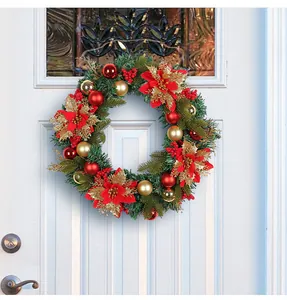 Detailed view of a large festive Christmas wreath with red flowers and gold ornaments on a door