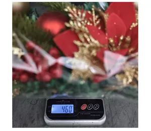 Macro view of a large red Christmas wreath on a scale showing a weight of 460 grams.