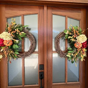 Close-up of two autumn wreaths with hydrangeas and pumpkins on a wooden door
