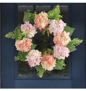Close-up of a pink and peach artificial hydrangea wreath hanging on a blue door window