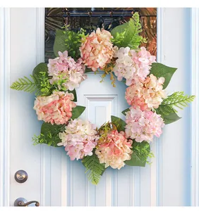Elegant pink and peach faux hydrangea flower wreath decoration hung on a white front door