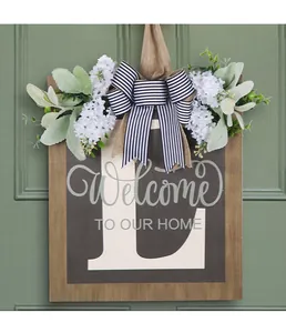 Dettaglio di una targa per porta in legno personalizzata con lettera L e fiori bianchi