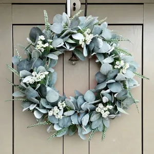 Detalle de corona de oreja de cordero artificial con flores blancas en puerta