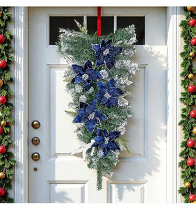 Elegante kersthanger met blauwe bloemen aan een witte voordeur