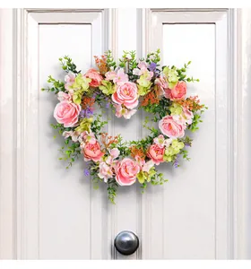 Pink rose heart-shaped wreath hanging on a white door for wedding decoration