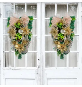 Detailed view of two elegant golden Christmas teardrop wreaths on a white vintage door