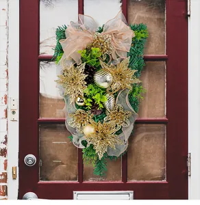 Gold Christmas teardrop wreath with champagne bow hanging on a red front door