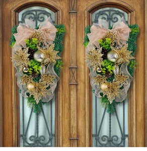 Pair of elegant golden Christmas swags with glitter flowers and bow on ornate wooden doors