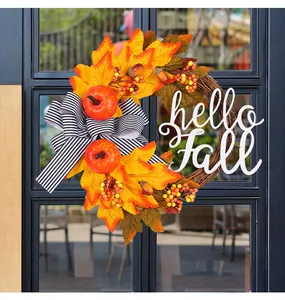 Detalle de corona de otoño con hojas de arce, calabazas y letrero de hello Fall
