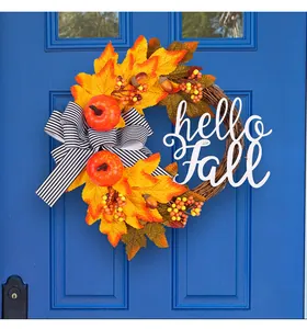 Primer plano de una corona de otoño con hojas de arce y calabazas en una puerta azul