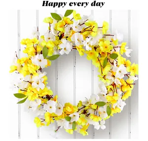 Close-up of a spring flower wreath with yellow and white blossoms on white wood.