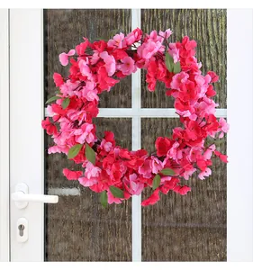 Detail view of a vibrant pink spring cherry blossom wreath hanging on a white door