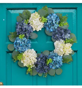 Detail of blue and white hydrangea wreath with green leaves on a turquoise door
