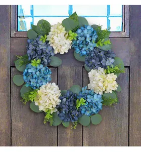 Close-up of a blue and white artificial hydrangea wreath on a rustic wooden door.