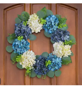 Close-up detail of artificial blue and white hydrangea wreath hanging on a brown wooden door