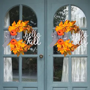 Decoratieve herfstkrans met esdoornbladeren en pompoenen en hello Fall bordje op de deur