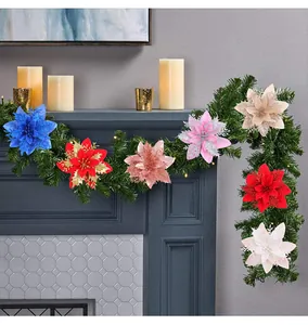 Artificial poinsettia flowers decorating a green garland on a fireplace mantel