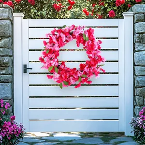 Beautiful vibrant pink cherry blossom wreath hanging on a white wooden garden gate