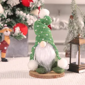 Festive green knitted Christmas gnome doll on a wooden base with a white beard