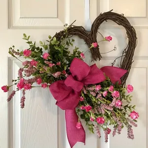 Detailed view of a hand-woven heart-shaped wreath with pink flowers and a large magenta bow.