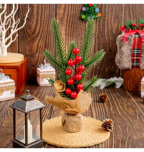 Gros plan d'un mini sapin de Noël de 25 cm avec baies rouges et base en toile de jute