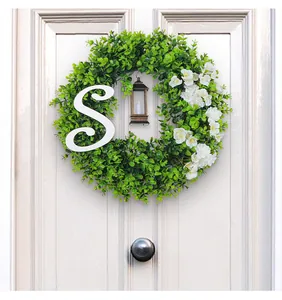 Gedetailleerd zicht op een eucalyptus kerstkrans met een witte letter S en een mini-lantaarn.