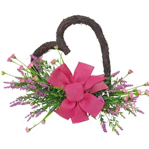 Heart-shaped woven wreath with artificial pink flowers and a large pink burlap bow decoration