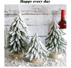 Nahaufnahme von drei beflockten Mini-Weihnachtsbäumen mit Holzsockel in einer Szene