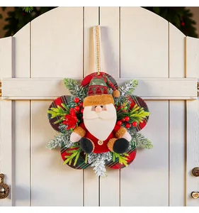 Vue détaillée d'une couronne de Noël avec un Père Noël en peluche sur une porte en bois blanc.