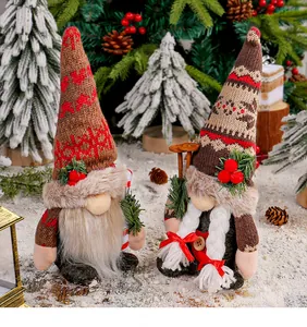 Vue détaillée de gnomes de Noël tricotés avec des bonnets à flocons dans la neige.
