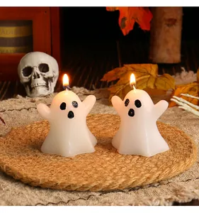 Lit white Halloween ghost candles displayed on a woven mat with spooky decorations